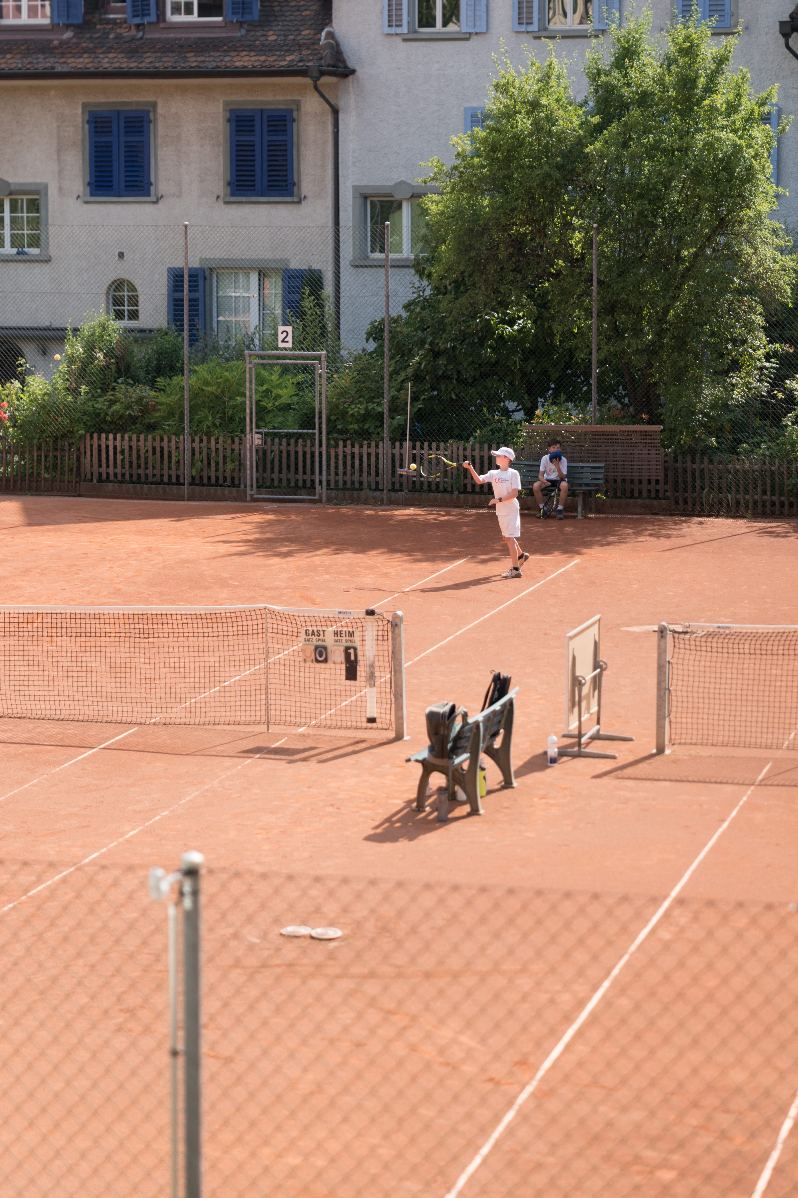 Ein Mädchen hält einen Tennisschläger vor einem grünen Hintergrund